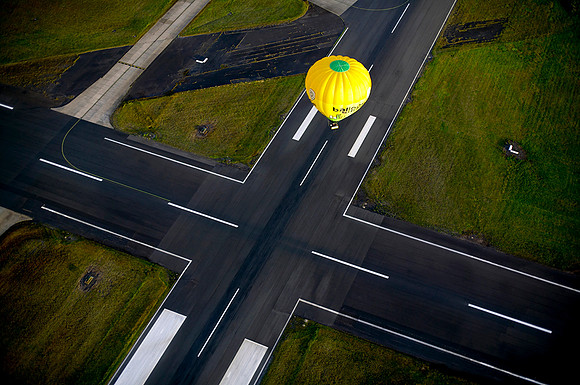 Airport runways intersecting, aerial view with hot air balloon landing